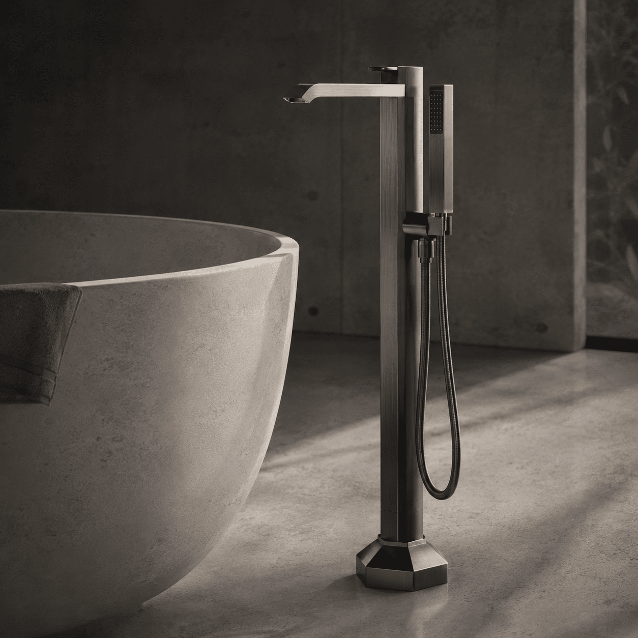 Monolithic freestanding bathtub filler finished in brushed gunmetal plating, anchored next to an independent solid-surface soaking tub, representing Skyland luxury architectural faucets matrix for elite residential villas.