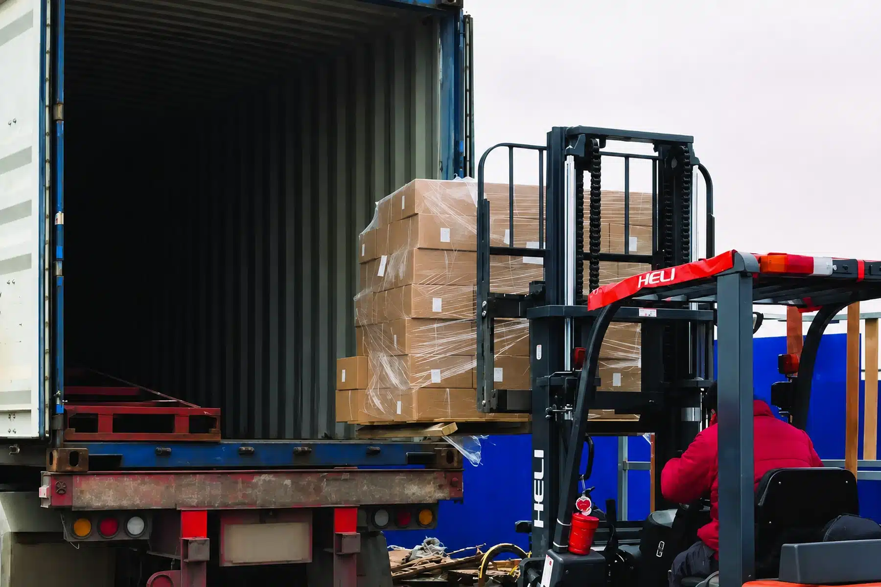 Forklift moving palletized building materials into a shipping container