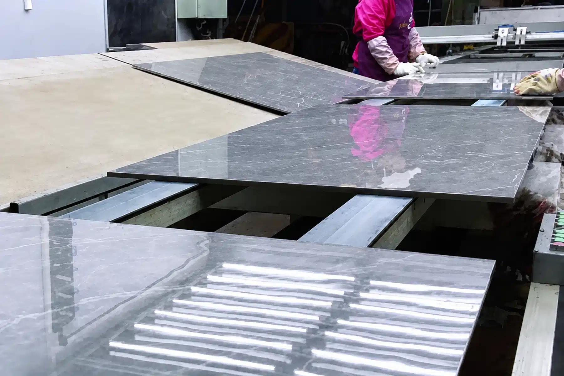 Stone slabs moving through a surface processing stage in a factory